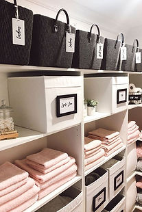 Neatly labelled baskets and boxes holding towels on white shelving